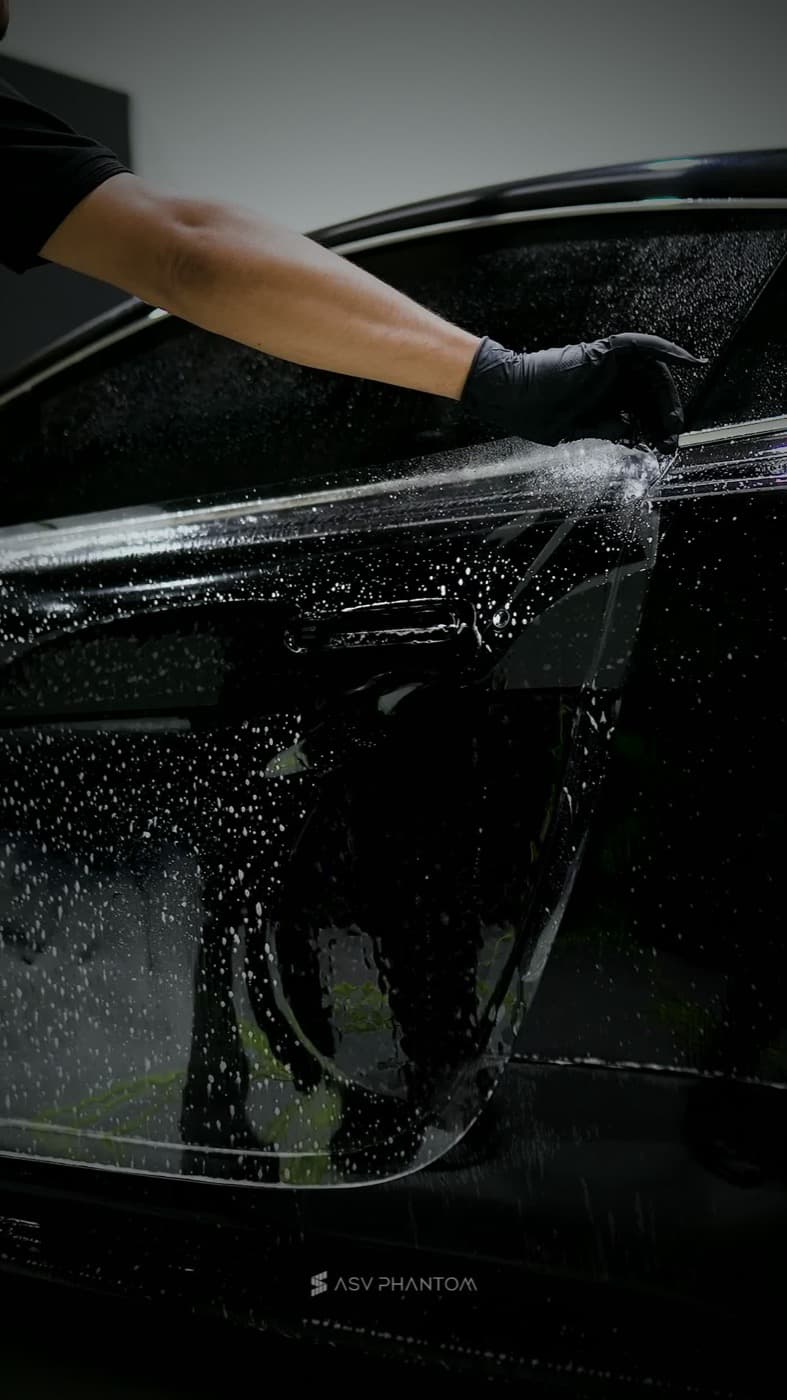 Clear paint protection film being hand-finished along a door edge